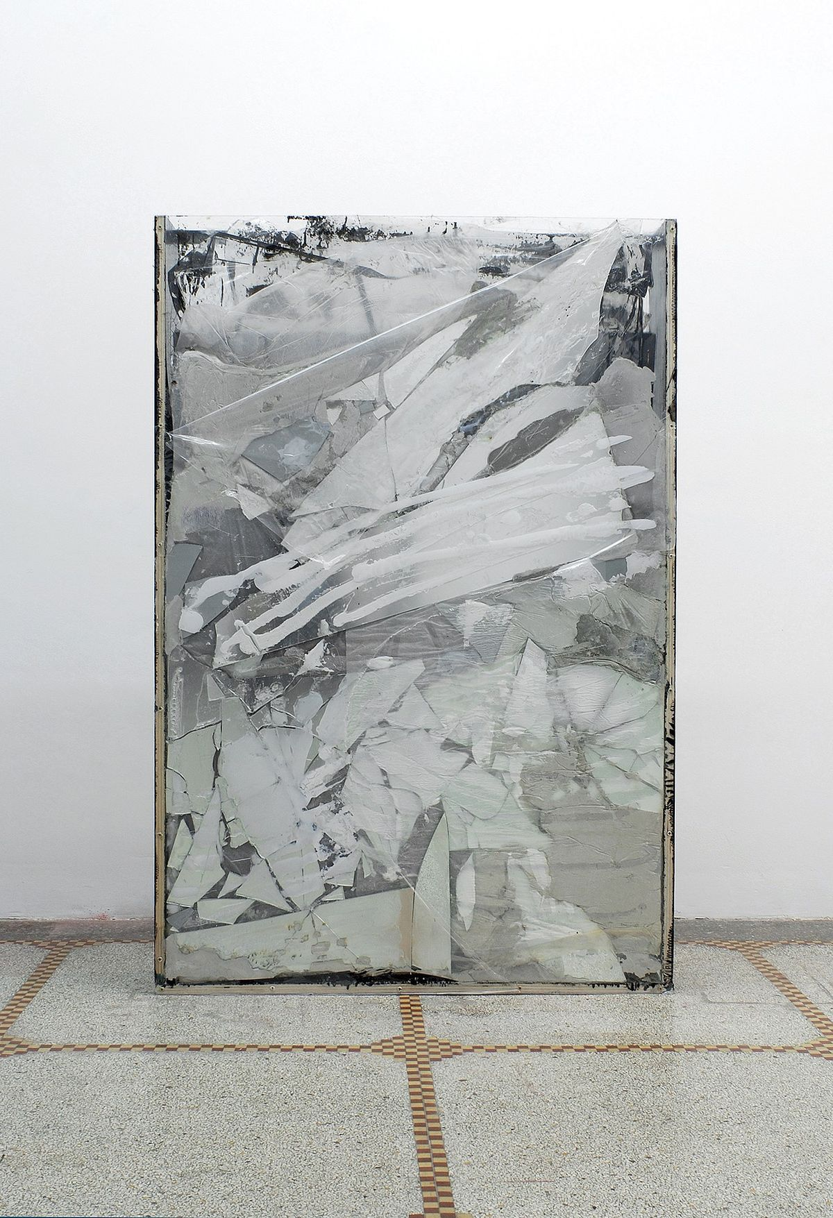 A reflective metal artwork leaning against a gallery wall